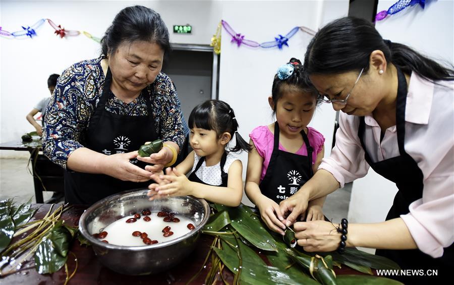 Residents make traditional zongzi, pyramid-shaped dumplings made of glutinous rice and wrapped in bamboo or reed leaves, during a community event to celebrate the upcoming Dragon Boat Festival in Beijing, capital of China, June 4, 2016.