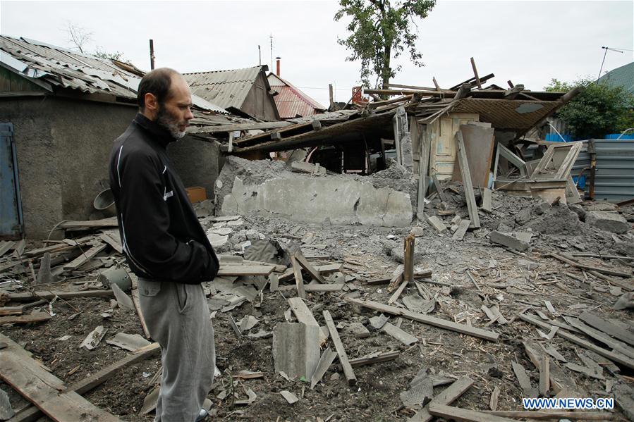 People stand in front of a damaged building in Donetsk, eastern Ukraine, June 9, 2016.