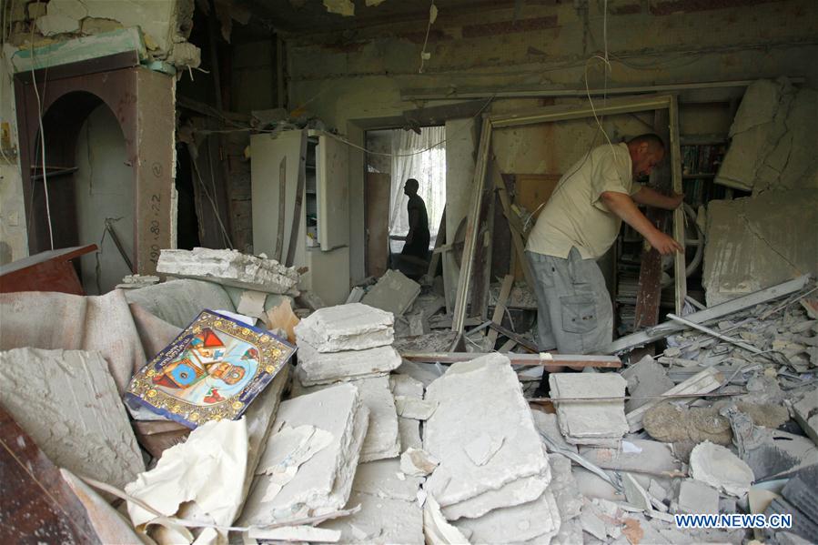 People stand in front of a damaged building in Donetsk, eastern Ukraine, June 9, 2016.