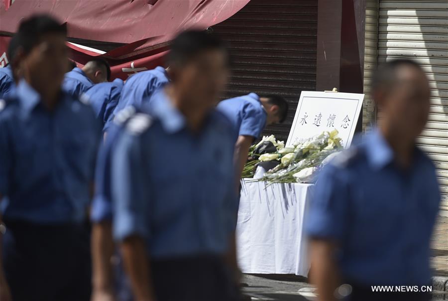 A memorial service is held at the fire site of an industrial building in Hong Kong's East Kowloon to pay tribute to Thomas Cheung, a 30-year-old senior station officer who died while battling the fire, in south China's Hong Kong, June 27, 2016. 