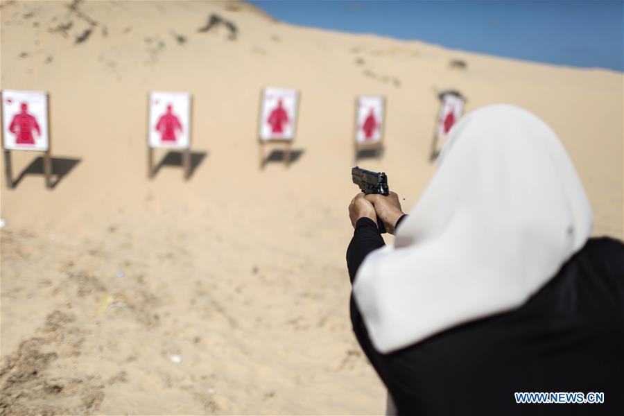 A Palestinian girl aims a pistol as she prepares to fire at a target during a training session for the families of Hamas officials, organized by Hamas-run Security and Protection Service, in Khan Younis in the southern Gaza Strip, July 24, 2016.