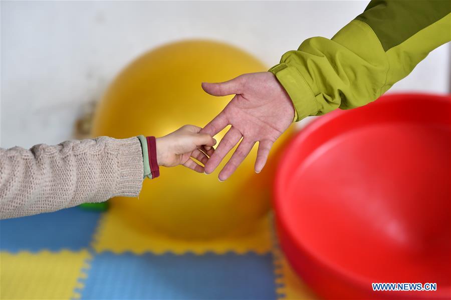 A child tries to hold his teacher's hand during a training course at a service center of the Lingxing community in Taiyuan, capital of north China's Shanxi Province, March 28, 2017. Established in 2010, the service center has accommodated over 60 children with autism. A total of 29 teachers take part in the rehabilitation program to help these children. April 2 marks the World Autism Awareness Day. (Xinhua/Zhan Yan) 