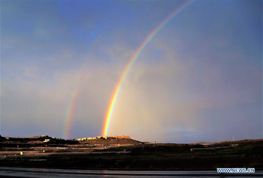 rainbow appears in sky over village following heavy rain in