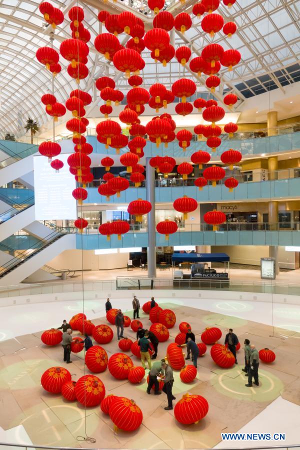 Staff members install red lanterns in Galleria Dallas shopping