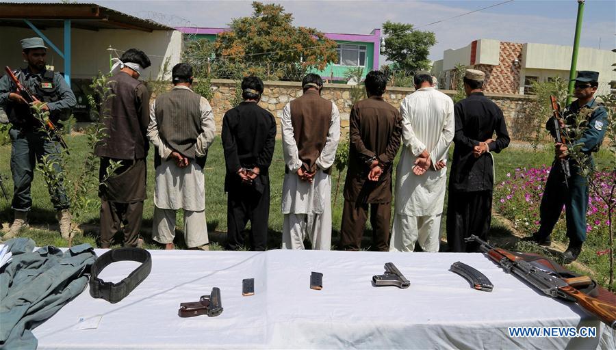 Suspected Taliban militants stand handcuffed behind weapons placed on tables in Ghazni province, Afghanistan, on July 27, 2016.