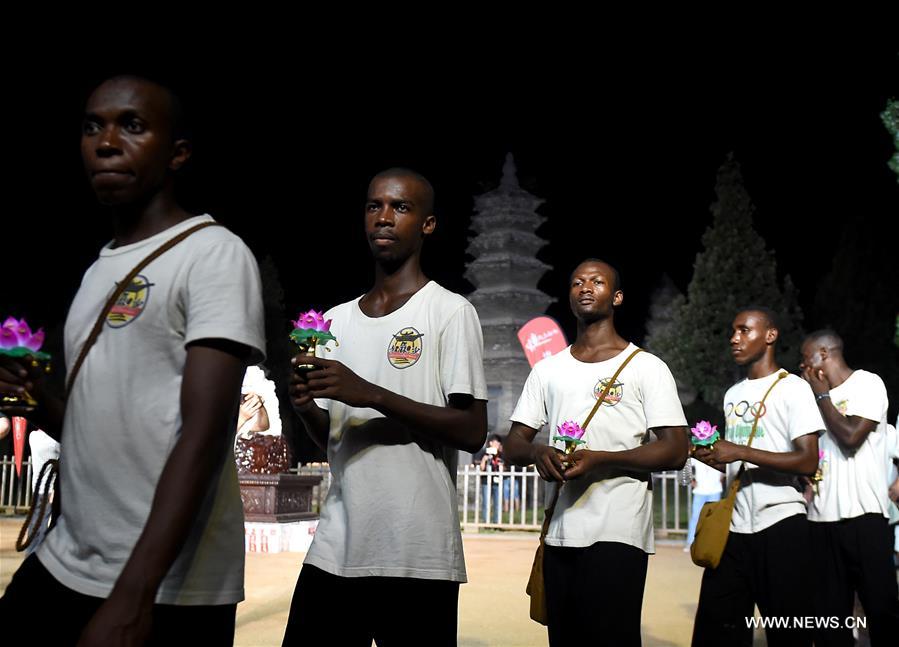 African apprentices carrying lotus-pattern lamps attend a buddhist ritual at the Shaolin Temple on the Songshan Mountain in Dengfeng City, central China's Henan Province, Aug. 13, 2016. (Xinhua/Li An)