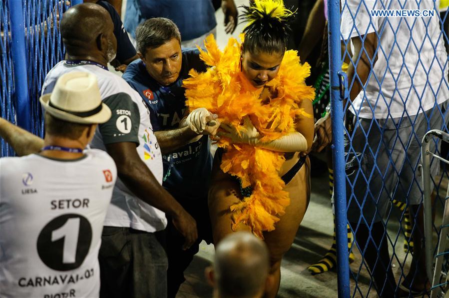 A rescuer helps a woman after the collapse of the top of an allegorical car of the samba school Unidos da Tijuca during the Carnival parade as it advanced through the Marques de Sapucai Avenue, in downtown Rio de Janeiro, Brazil, on Feb. 28, 2017.