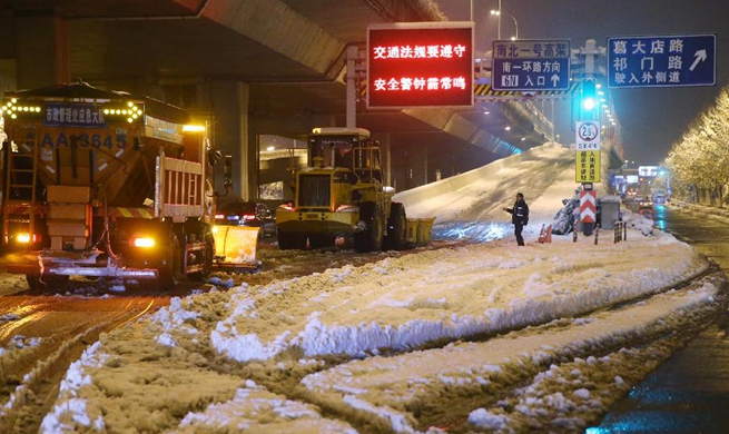 Staff members clear off snow in E China