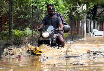 People wade through waterlogged street in Guwahati, India