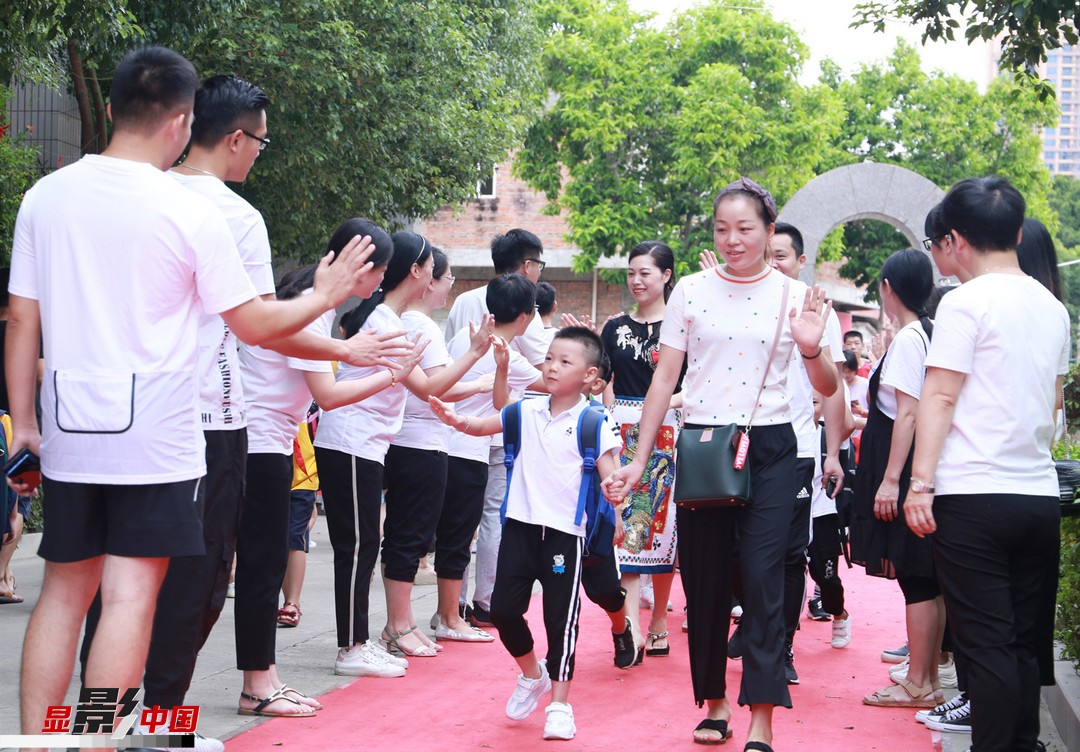 9月1日,在福建石狮市宝盖镇塘边小学,学校老师在校门口与新入学的孩子